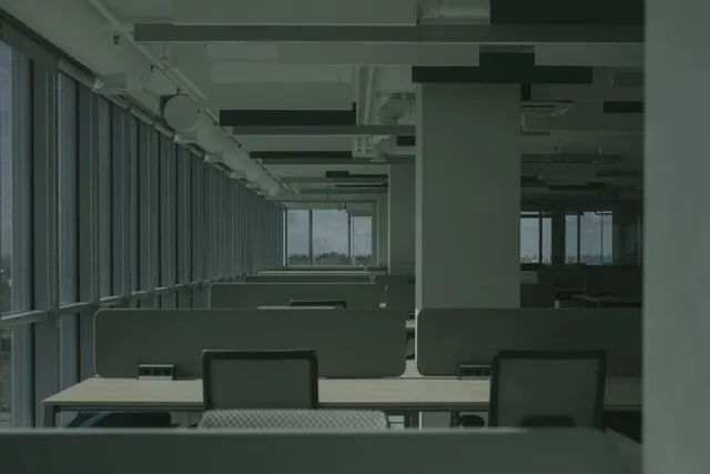 Spacious empty office with rows of desks and large windows. Gewerberaum mieten in Österreich: Vertragsarten, Kosten und Pflichten